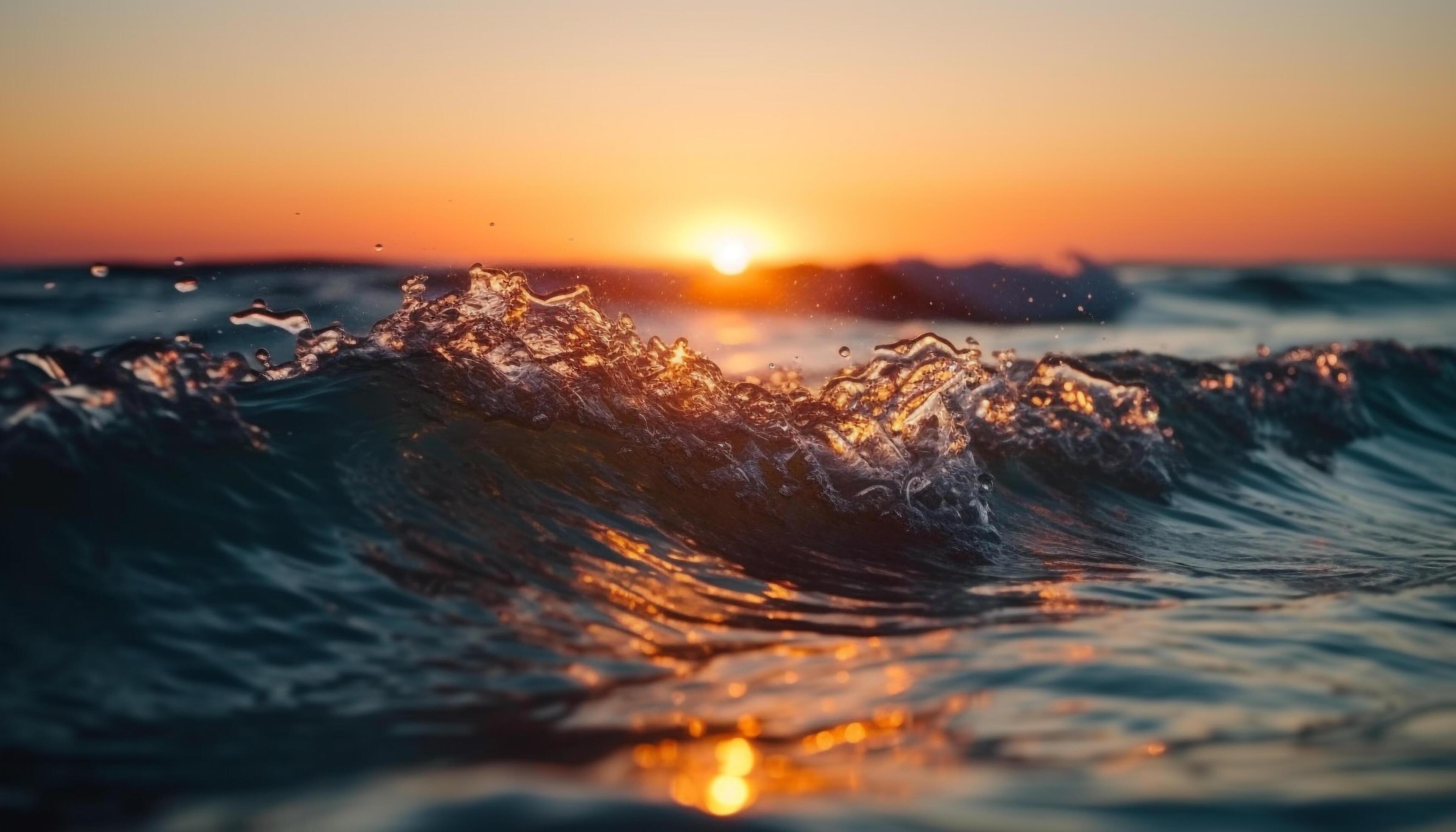 Close-up of an ocean wave cresting and breaking at sunrise with golden light on the horizon and dark teal water